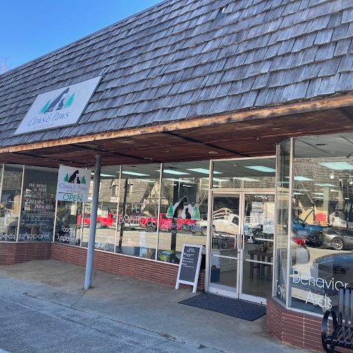 Front of a pet supply store with brick exterior, large glass windows, and a sloped shingled roof; sign reads Claws & Paws. - Clayton, GA