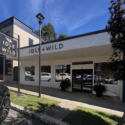 Front of Idle + Wild store with white facade, large windows, and a sign reading Idle + Wild Home & Gifts. - Clayton, GA