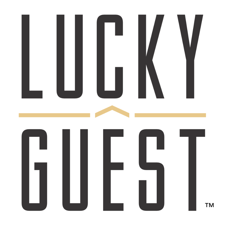 Lucky Guest logo: tall black letters spell 'LUCKY' above 'GUEST' with a beige chevron between and beige lines on either side. - Clayton, GA