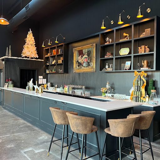 Cozy indoor bar/café interior with a long white counter, brown bar stools, dark paneling, and Christmas decorations including a tree on the left shelf area. - Clayton, GA