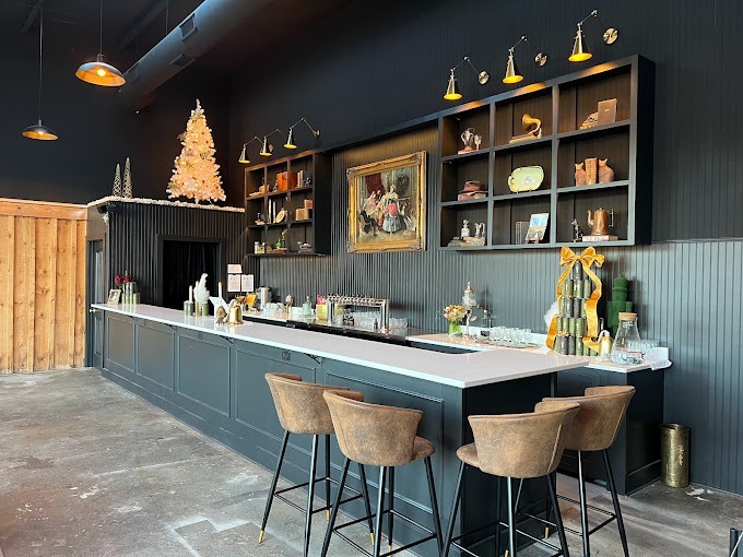 Cozy indoor bar/café interior with a long white counter, brown bar stools, dark paneling, and Christmas decorations including a tree on the left shelf area. - Clayton, GA