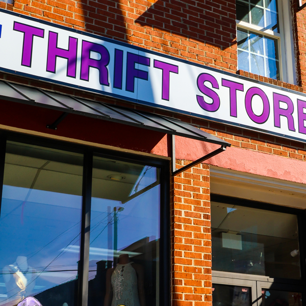 Storefront with a bold 'THRIFT STORE' sign on a red brick building and a Faith anti-abuse banner above. - Clayton, GA