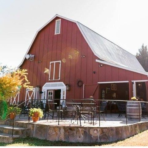 Red barn with white trim and metal roof, outdoor seating on a raised stone patio. - Clayton, GA