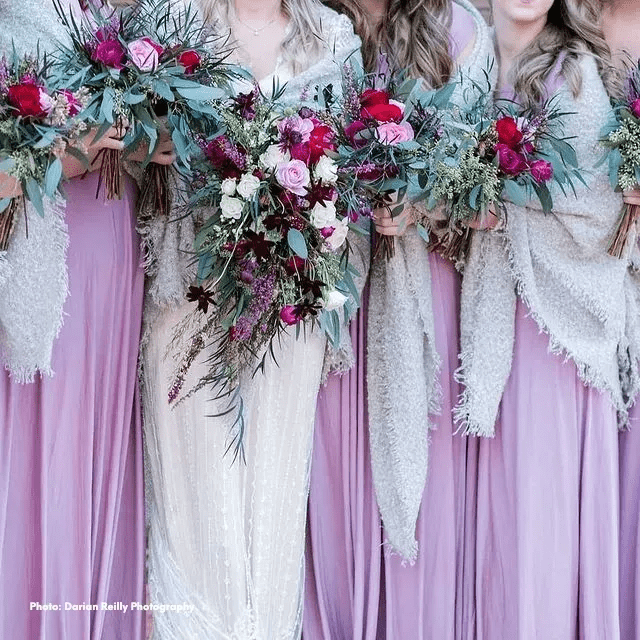 Bridesmaids in lavender gowns hold large bouquets of pink, burgundy, and white flowers with greenery. - Clayton, GA