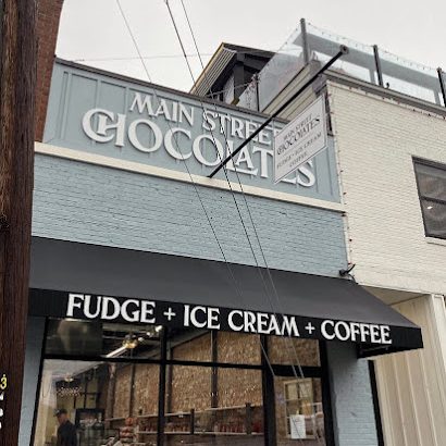 Storefront with a light blue facade and a sign that reads 'Main Street Goods', plus a black awning that says 'Fudge + Ice Cream + Coffee' - Clayton, GA