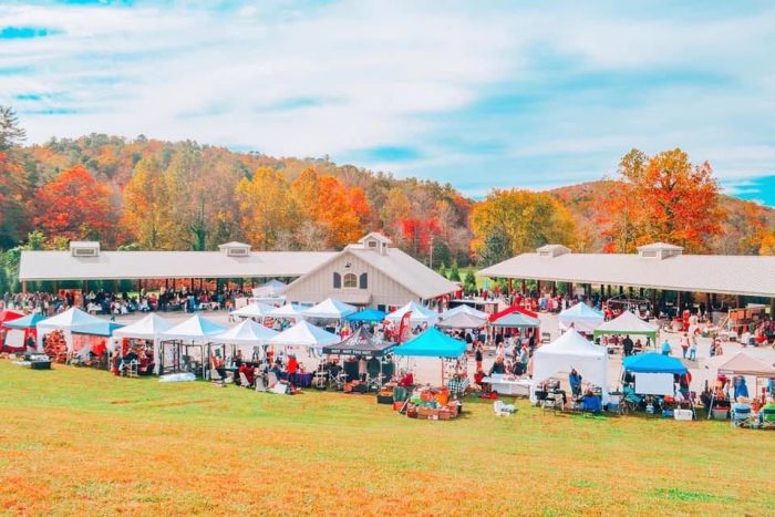 Sassafras Artisan Market Outdoor autumn market with numerous white tents and vendors on a grassy field, colorful fall trees in the background. - Clayton, GA
