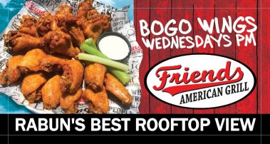 Tray of fried chicken wings on newspaper with celery sticks and dipping sauce, beside a red wooden sign for Friend American Grill and a bottom rooftop view banner. - Clayton, GA
