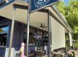 Exterior view of Rabun Social restaurant with a large black sign showing a tiger wearing sunglasses and the text ‘Kitchen Cocktails Sushi,’ outdoor seating under a covered patio.