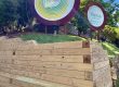Circular sign with Thrive logo and green/yellow concentric rings, set on a wooden frame outdoors at Thrive Wellness Hub.