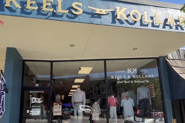 Storefront of Keels & Kollars clothing shop with large sign, glass display window showing mannequined outfits and a patriotic display outside in Clayton, Georgia.