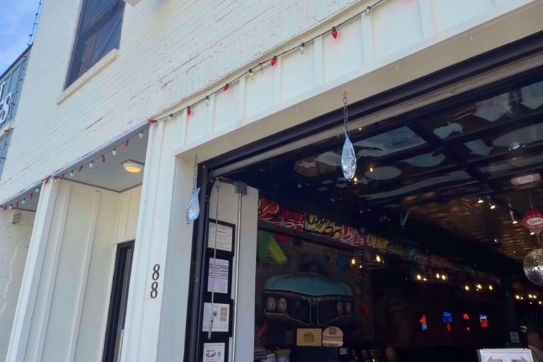 Open storefront with a vertical 'FRIENDS' sign on white brick, large garage-style door revealing a vintage car inside and memorabilia.