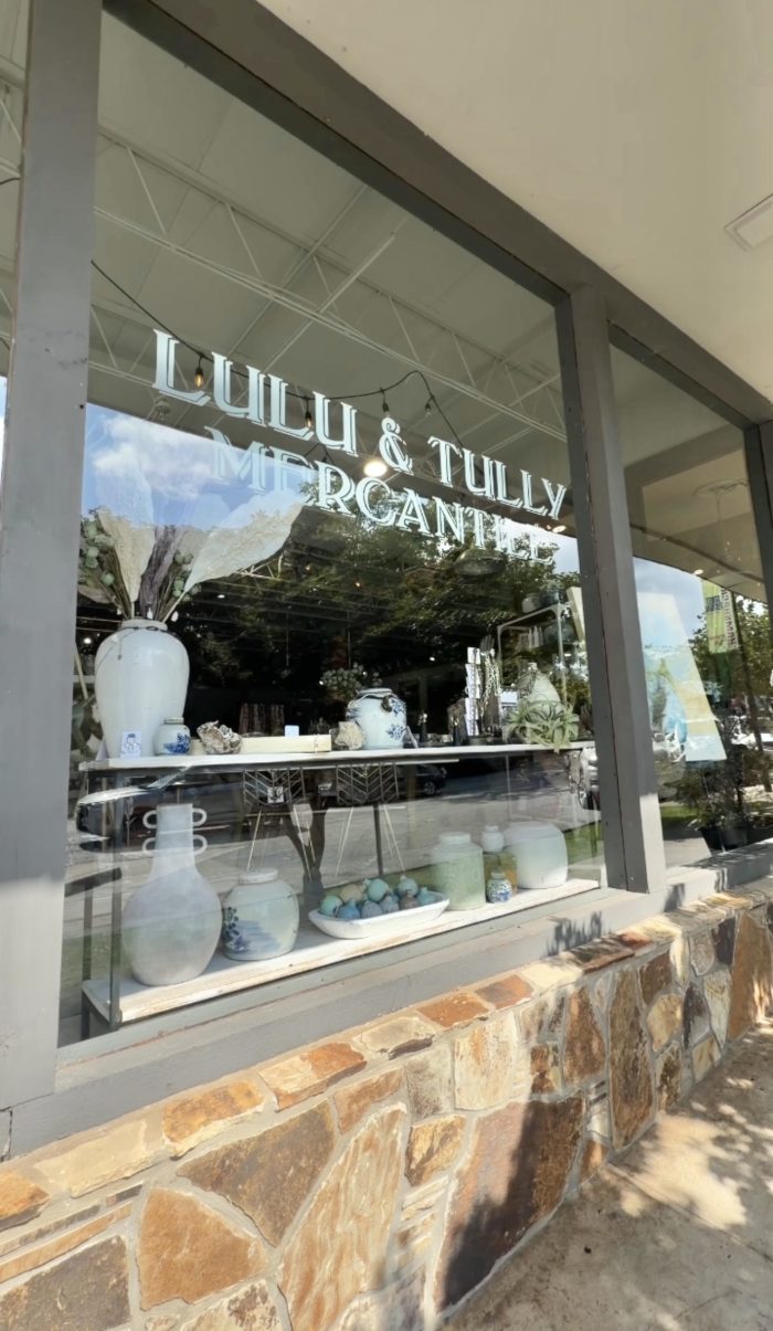 Storefront window display at Lulu & Lily Mercantile featuring blue-and-white ceramic vases and bowls arranged on a shelf inside.