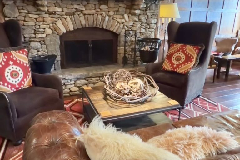 Cozy living room with a stone fireplace, leather sofa, and colorful hanging lanterns above a wooden coffee table.