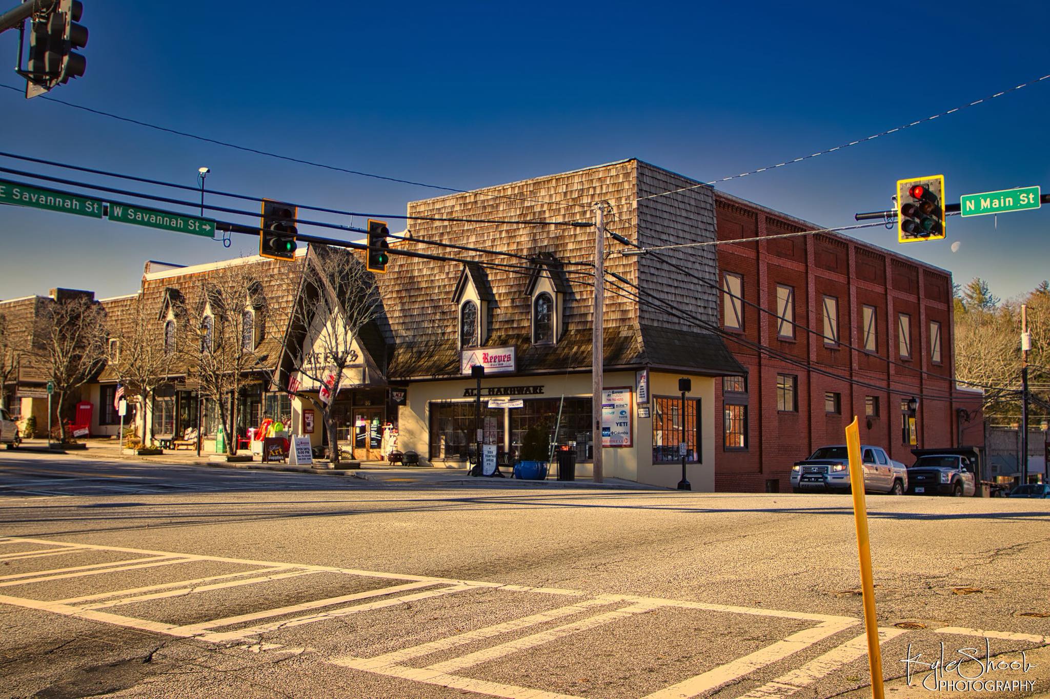 Reeves Hardware - Visit Clayton, GA Intersection at N Main St and W Savannah St with brick buildings, traffic lights, and a yellow street pole in the foreground - Clayton, GA