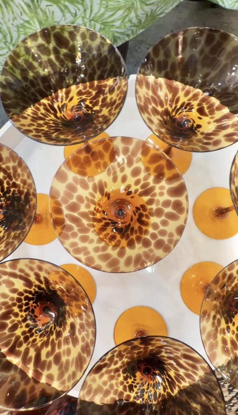 Overhead view of leopard-print glass bowls with orange bases arranged on a white table, seen from above.