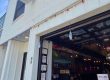 Open storefront with a vertical 'FRIENDS' sign on white brick, large garage-style door revealing a vintage car inside and memorabilia.