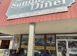 Front of Sunday Diner with a large gray sign reading 'Sunday Diner' above outdoor seating. - Clayton, GA