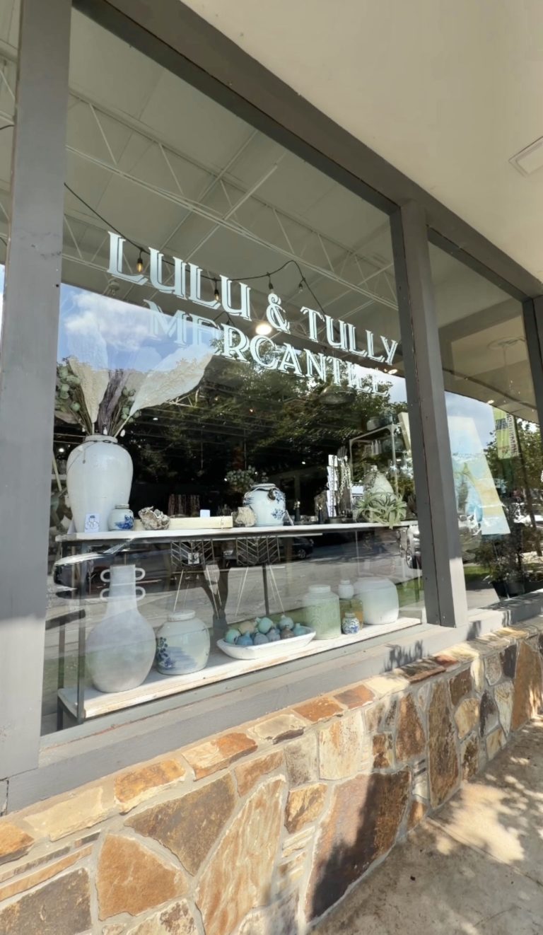 Storefront window display at Lulu & Lily Mercantile featuring blue-and-white ceramic vases and bowls arranged on a shelf inside.