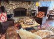 Cozy living room with a stone fireplace, leather sofa, and colorful hanging lanterns above a wooden coffee table.