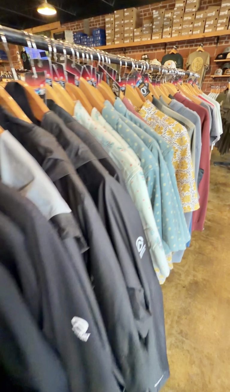 Outdoor shirts and apparel on a clothing rack inside Outdoor 76 in Clayton, Georgia
