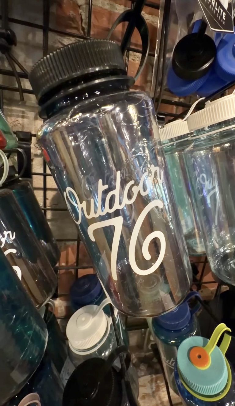 Outdoor 76 branded water bottle displayed among drinkware in the Clayton store